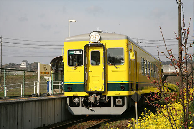 Shiromigaoka Station in early spring with the Isumi 350 series and a view of Otaki Castle in the distance